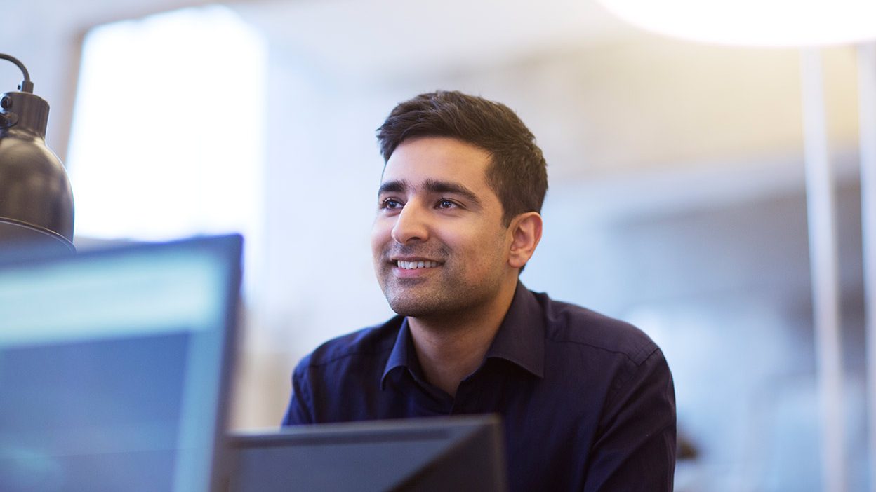 Professional portrait of a smiling man in an office environment.