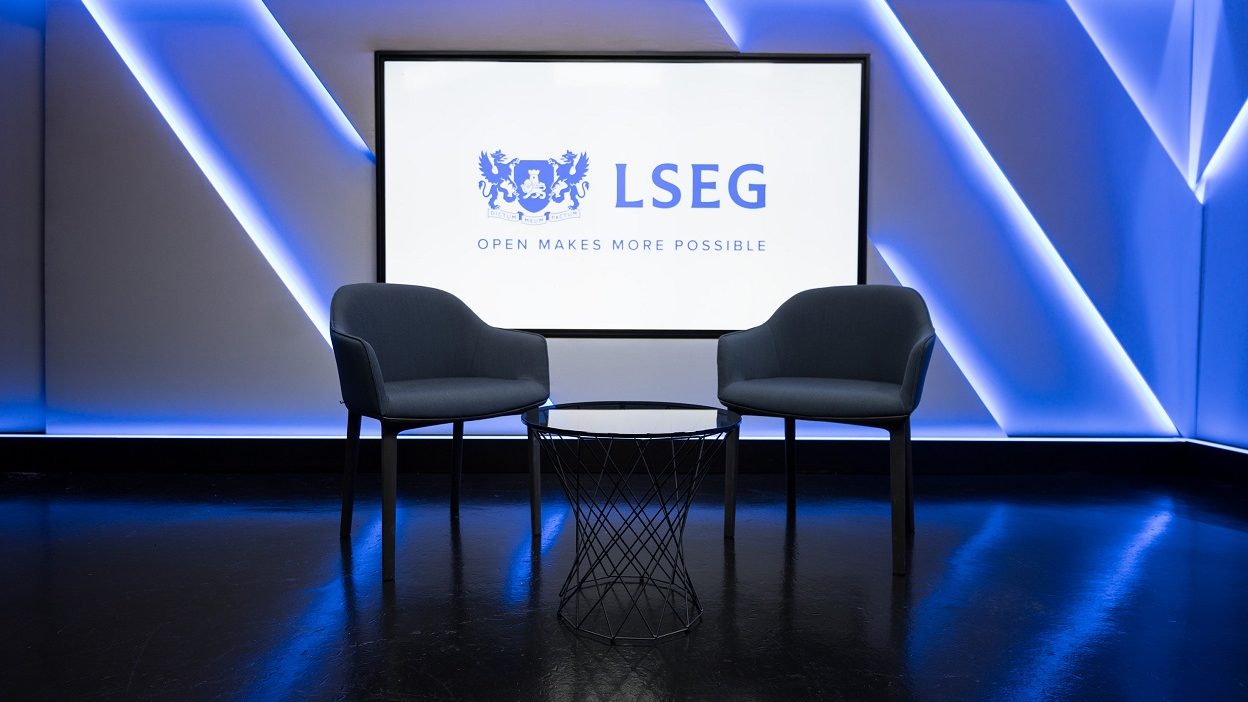 Studio 4 wide shot, two chairs around a small glass coffee table. Screen behind hosts the LSEG logo with a caption ‘Open Makes More Possible’